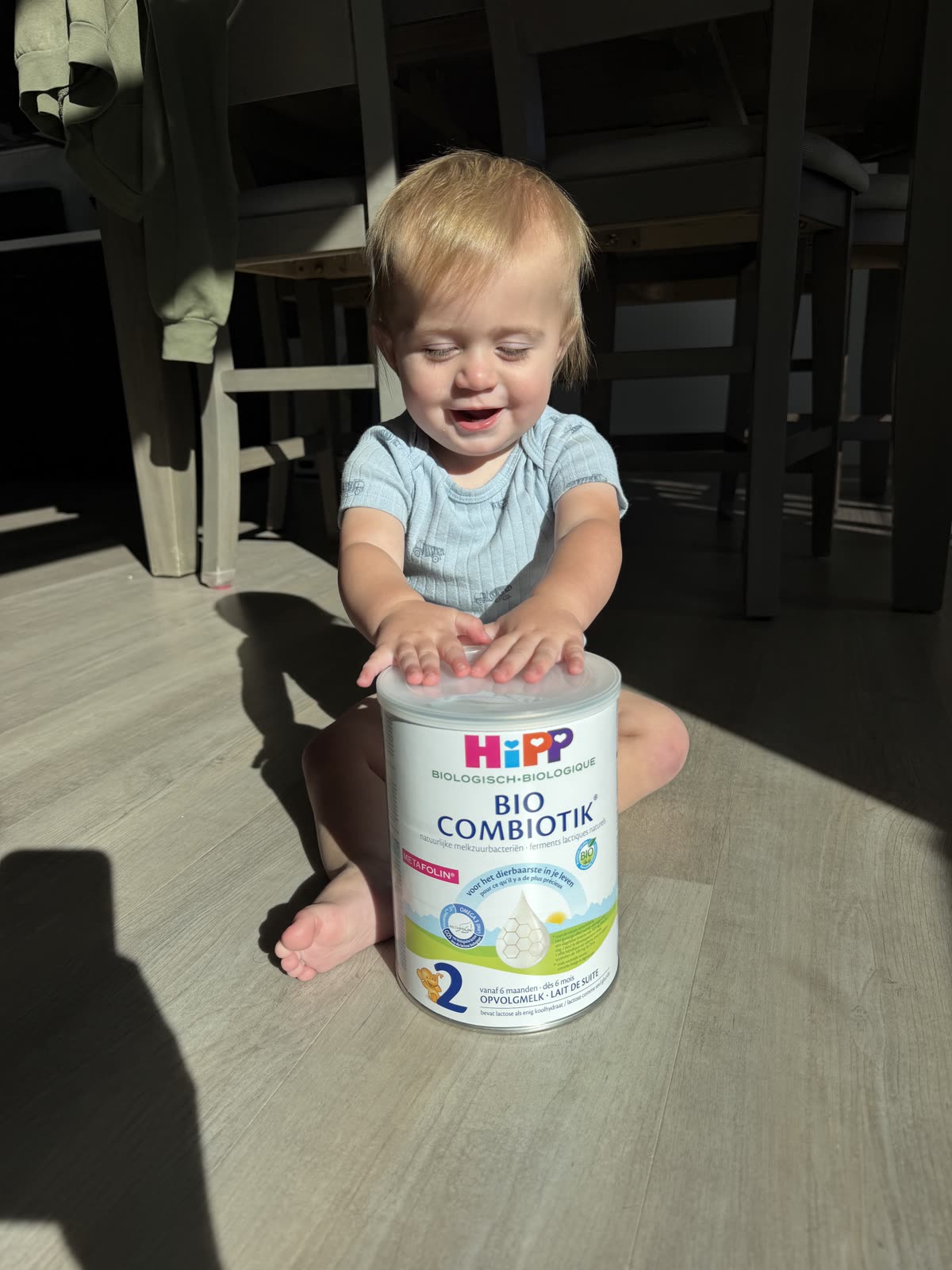 Tatum's youngest sitting on the floor with a can of HiPP Dutch