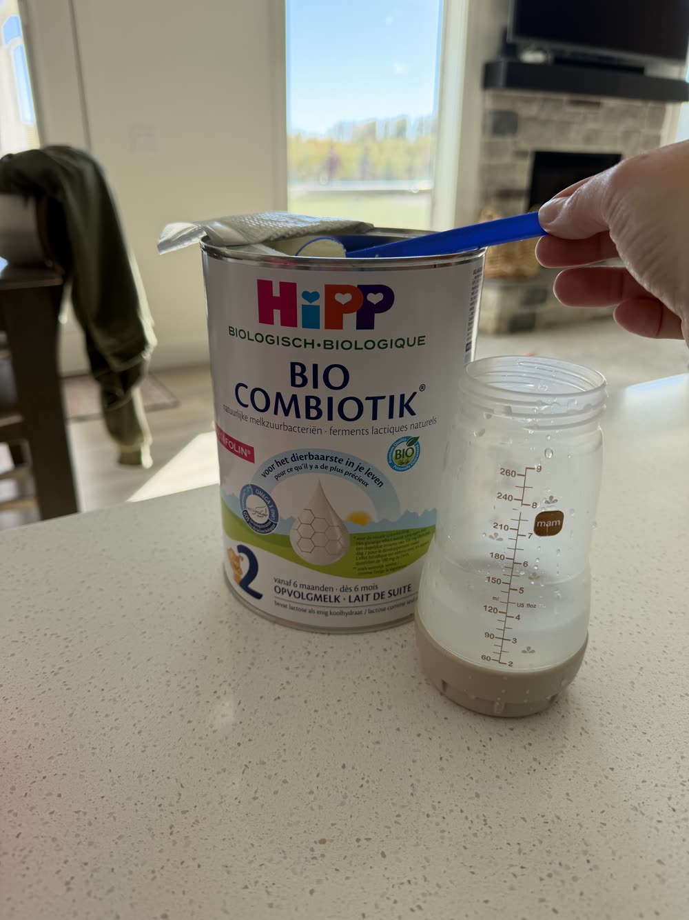 Tatum measuring a scoop of HiPP Dutch into a bottle